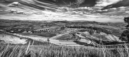 Panoramic view at curved mountain road under the mountain peak. Black and white