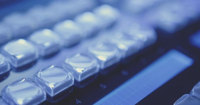 Close-up focus shift change via transparent buttons of control studio in blue light of broadcast audio video studio