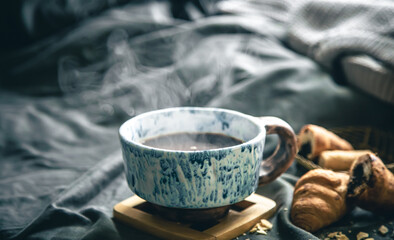 Fototapeta na wymiar A cup of hot tea and croissants on a blurred background in bed.