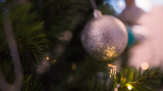 Beautiful decorations on the Christmas tree illuminated by a garland close-up. Slow motion.