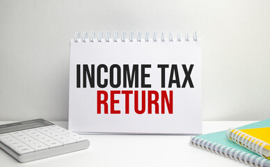 income tax return words on paper notebook with office supplies
