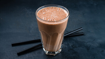 Coffee and banana smoothie in a transparent glass goblet.