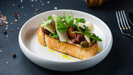 Bruschetta with beef slices, capers, cherry tomatoes, parmesan cheese, parsley.