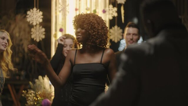 young african woman dancing in merry Christmas party, pretty lady in black dress, enjoying music