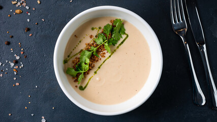 Cauliflower cream soup with fried onion, parsley and green oil.