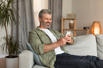 New normal for retired people. Smiling old caucasian male typing on smartphone uses new app for chat