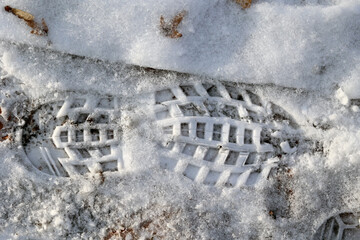 Ślad spodu buta odciśnięty na śniegu w lesie. 