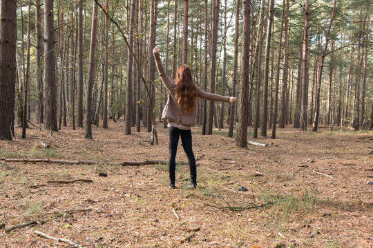 A young woman communing with nature in a forest in Autumn.