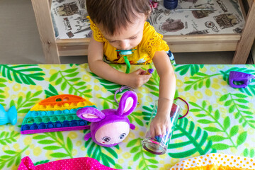Un bébé fille en robe jaune découvre des objets sur une table