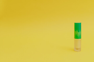 Lipstick with a bright green cap on a yellow background