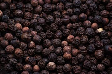 Background made of dried black pepper balls. Close-up macro shot.