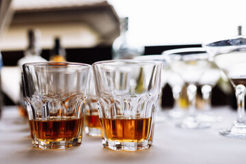 a lot of glasses with cognac, brandy or whiskey stand on the bar. Various alcoholic beverages in glasses on party