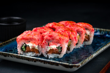 Set of Japanese maki sushi rolls with tuna tartare, salmon, cream cheese, avocado, cucumber, red flying fish caviar and soy sauce.