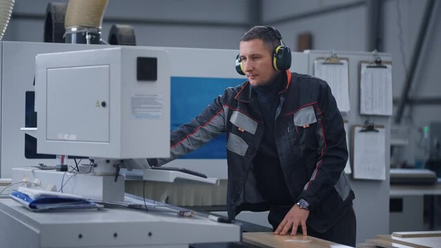 professional engineer is controlling milling machine in woodworking shop of furniture factory
