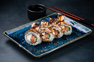 Set of Japanese sushi rolls with salmon, bacon, cream cheese, cucumber, sesame, teriyaki sauce and soy sauce.