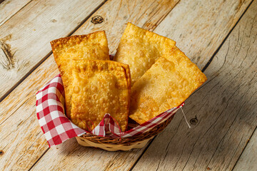 brazilian pastel, fried snack on a bowl or container, over wooden table