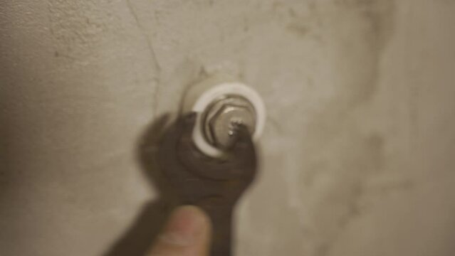 A man's hand uses a wrench to tighten a stub nut. DIY