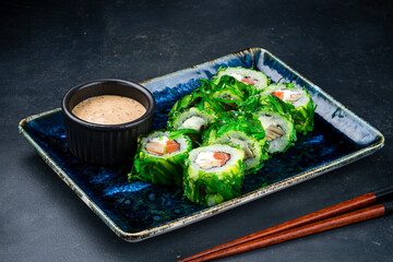 Sushi rolls with salmon, cream cheese, tamago omelet in marinated chuka seaweed and sauce.