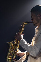 Fototapeta na wymiar A European man plays the saxophone in the dark.