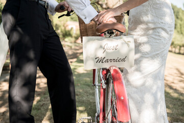 A bride and groom push a bicycle with a Just Married sign on the back