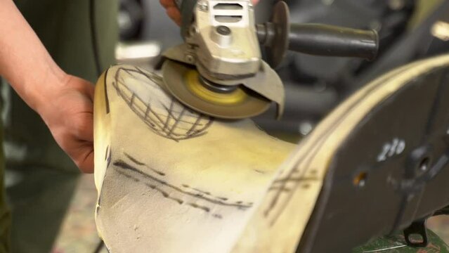 Close-up front view of a male mechanic repairing a motorcycle seat in a garage. Seat adjustment.