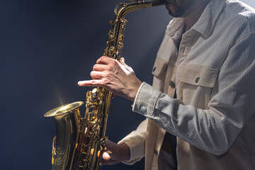 Obraz na płótnie Canvas Male musician on stage plays the saxophone dark with smoke.
