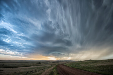 Storm clouds gather over a road that leads into the distance, creating a very dramatic landscape; North Dakota, United States of America