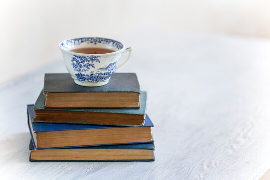 Teacup on pile of vintage books.