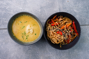 Lunch udon noodles with pork and vegetables and ramen soup with coconut milk, chicken and curry
