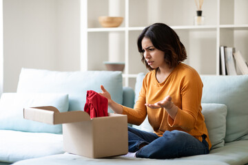 Wrong Parcel. Confused arab woman looking at open cardboard box at home