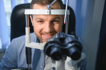 Handsome man getting an eye exam at ophthalmology clinic. Checking retina of a male eye close-up