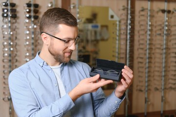 Young man choosing spectacles at optic shop