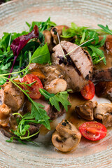 Restaurant menu veal medallions with mushrooms, arugula, cherry tomatoes and sauce, closeup.