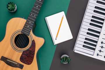 Acoustic guitar, musical keys and a blank notepad on a colored background.
