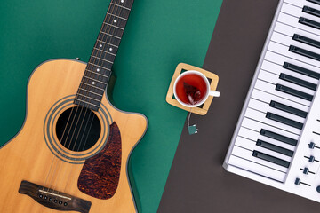 Guitar, musical keys and a cup of tea on a colored background, top view.