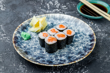 Maki roll with salmon on a grey table