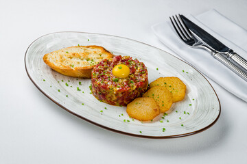 Tartare from beef with croutons on white table