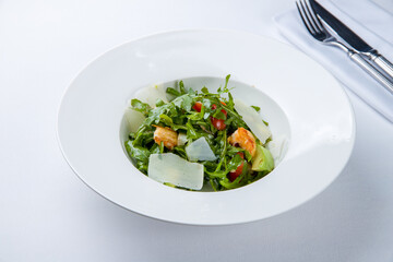 Arugula with shrimps and avocado on a white plate