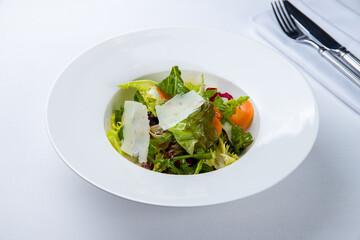 Green vegetable salad with parmesan on a white plate