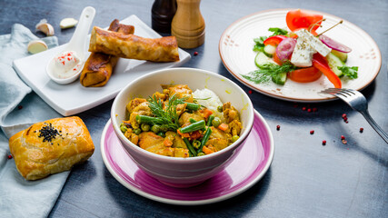 Butter chicken curry tikka masala Korma, pancakes, greek salad and samsa on blue table