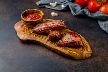 Barbecue pork ribs with sauce on wooden board on dark brown table