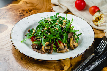 Steak salad with beef and aragula on wooden table