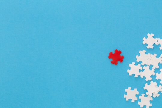 White puzzles and one red on a blue background, flat lay.