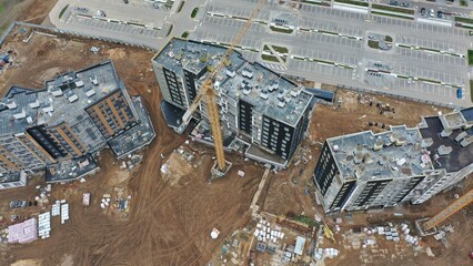 Minsk, Belarus - 30.11.2022: Construction in the rain of a high-rise residential building in Europe. Eastern Europe. Autumn at a high-rise construction site. A crane is building a multi-storey house