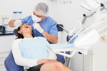 Portret of male dentist and woman patient sitting in medical chair during checkup at dental clinic office