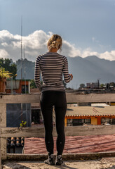 A young girl stands on the balcony and admires the beautiful view of the mountains in the rays of...