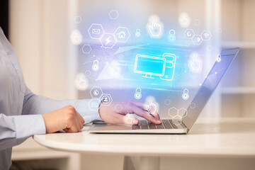 Hands working on laptop with digital icons