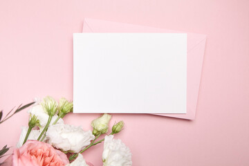 Obraz na płótnie Canvas Holiday greeting card mockup with envelope and white flowers on pink background, top view, flat lay. Blank wedding invitation card mockup and floral decor