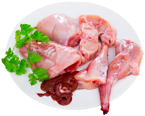 Chopped fresh raw rabbit on plate with greens prepared for cooking. Healthy dietary food. Isolated over white background