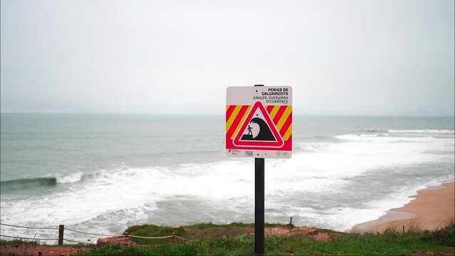 Danger sign warning about big sea waves in Nazare, Portugal Handheld